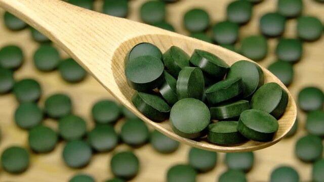 Spirulina (chlorella) green tablets rotation background. Close up