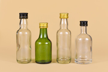 Different empty green and  white glass bottles on beige background