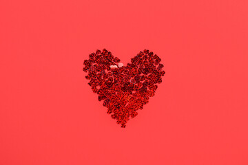 Heart made of beautiful confetti on red background. St. Valentine's Day