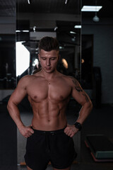 Fototapeta na wymiar Strong handsome man bodybuilder trainer with hairstyle and naked sexy muscular body in the gym