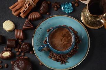 Coffee cup, beans, chocolate on old kitchen table Assortment of dark, white and milk chocolate sweets, zefir (zephyr). Spices, cinnamon.