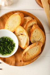 Plate of tasty croutons and bowl with sauce on white wooden background
