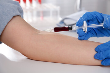 Nurse drawing blood sample from patient in clinic, closeup