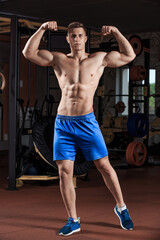 Man standing strong in the gym and flexing muscles