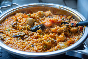Paella traditional Spanish food. Seafood paella in the fry pan with mussels, prawns, langoustine and squids. Cooking paella outside, closeup. Mediterranean seafood dish