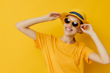 photo pretty girl in sunglasses a yellow t-shirt and Hat summer style yellow background