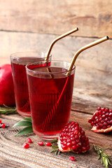 Glasses of delicious pomegranate juice on wooden background