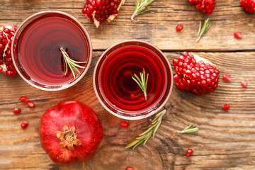 Glasses of delicious pomegranate juice on wooden background
