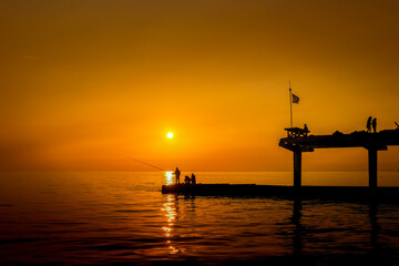 Fishermen on the seashore against the backdrop of sunset.