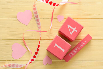 Calendar with date of Valentines Day and paper hearts on yellow wooden background