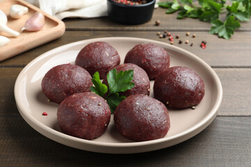 Many fresh raw meatballs on wooden table