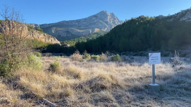 "military field, do not enter" french sign and Montagne Saint-Victoire in the Roques-Hautes departmental park in Provence, France