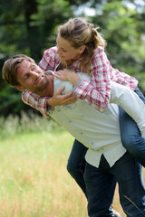 Fototapeta premium man giving lady a piggyback in the countryside