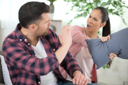woman hitting man with cushion during argument