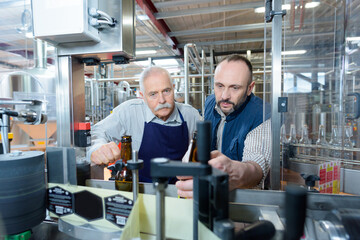 Naklejka na ściany i meble two men by labelling machine in bottling plant