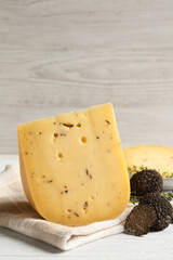 Delicious cheese, thyme and fresh black truffles on white wooden table. Space for text