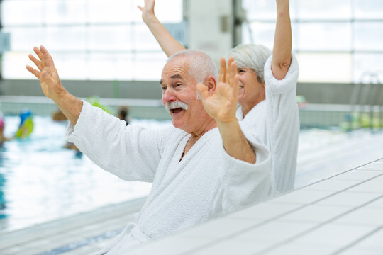 senior couple waving in a swimming pool