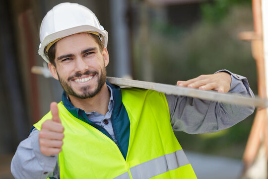 Worker At Carpentry Shop Smiling And Carrying Wood