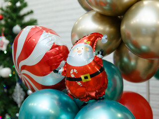 New Year or Christmas decoration from balloons of traditional holiday colors red, green, gold. A ball in the form of a cheerful Santa Claus. Christmas background
