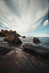 piece of the shore of Lake Jatkonjarvi at sunset in Koli National Park, eastern Finland. View of the rocks surrounded by clear clear water and beautiful sky with small streaks of clouds