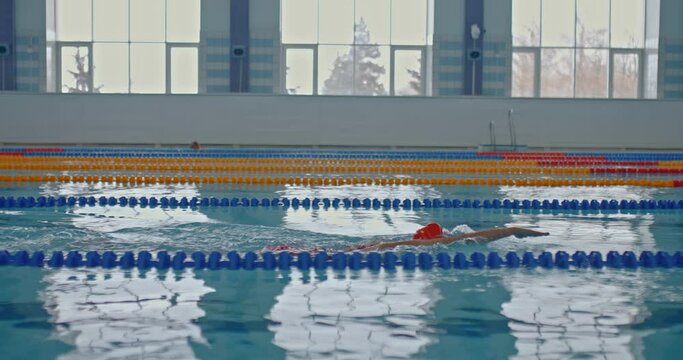 Woman swimmer professionally swims in the pool, water crawl style. Woman takes a breath and dives into the water, rowing with her hands. Training in the sports pool. 4k, ProRes