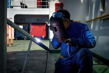 Welder is Welding process with sparks by MIG torch on board a ship