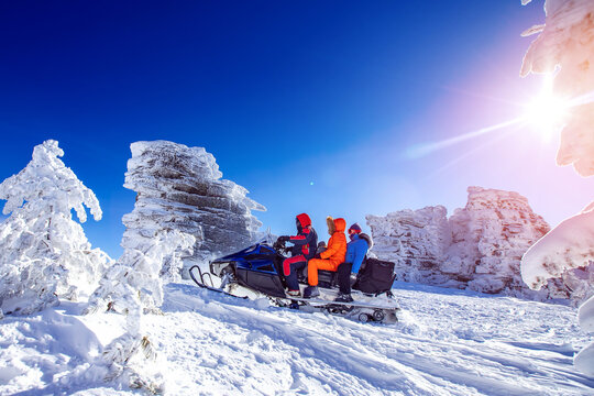 Concept travel tourist group snowmobile tour in frozen forest. Polar arctic snow mountains with sun light