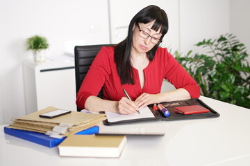 Sekretärin schreibt am Schreibtisch mit Brille