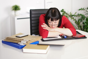 Sekretärin müde am Schreibtisch mit Brille