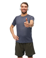 Fototapeta premium fitness, sport and healthy lifestyle concept - smiling man in sports clothes with headphones listening to music and showing thumbs up over white background