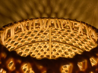 close-up shot of brown vintage rattan lamp with its circle light shadow on the wall in the night time