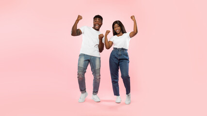 Portrait of excited young black couple shaking clenched fists