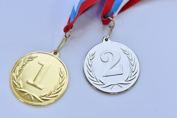 two medals for 1st and 2nd place on a white-blue-red ribbon on a gray background
