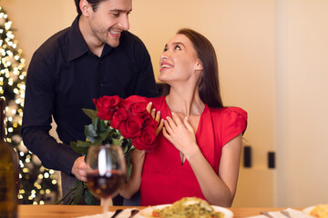 Young handsome man giving red roses to woman