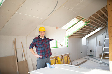 drywall worker with yellow safety helmet works on building site in a house