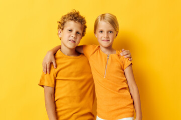 Cute preschool kids in yellow t-shirts standing side by side childhood emotions yellow background unaltered