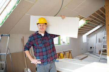 drywall worker with yellow safety helmet works on building site in a house