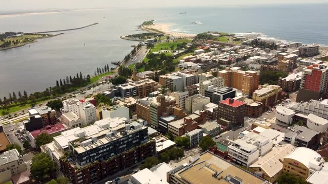Aerial drone city CBD shot of Newcastle Harbour Break wall tourism Nobbys Beach buildings Newcastle tourism NSW Australia 4K