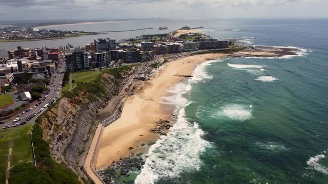 Aerial drone shot of scenic sandy Newcastle Beach Merewether City CBD Harbour break wall Tourism Pacific Ocean NSW Australia 4K