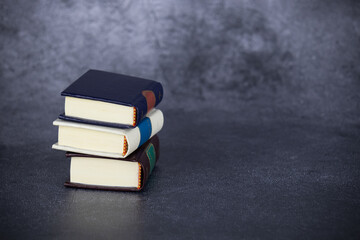Three thick books in stack on gray background