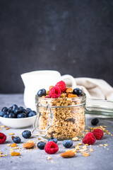 Granola with fresh berries in the glass jar. Healthy dessert or snack.