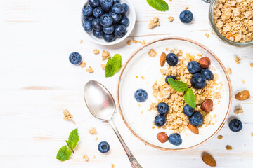 Yogurt granola with blueberries on white wooden table. Top view with copy space.