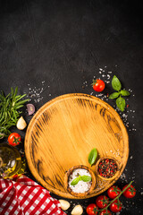 Food cooking background at black. Cutting board, spices, herbs and vegetables. Top view with copy space.