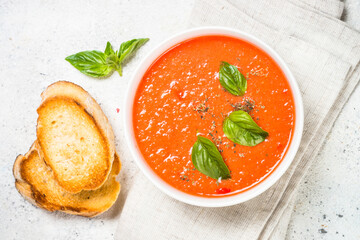 Tomato soup or gazpacho with basil. Summer cold vegan dish. Top view at white background.