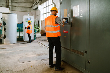 Multiracial man and woman working with equipment at factory