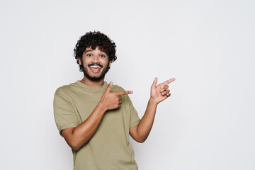 Young middle eastern man smiling and pointing fingers aside