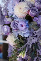 Wedding ceremony decorations: close-up decor of arch, decorated with crysanthemums, roses, hydrangeas and greenery. A lot of flowers in trendy color of the year 2022 - Very Peri.