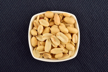 peeled salted peanut in bowl on blue background