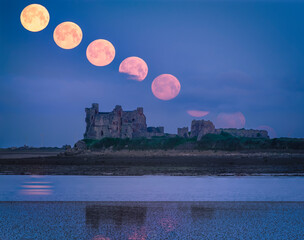 A castle with a super moon setting behind in stages