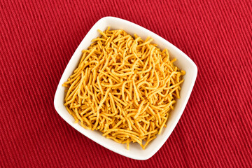 Top View of Aloo Bhujiya Namkeen in Bowl on Red Placement